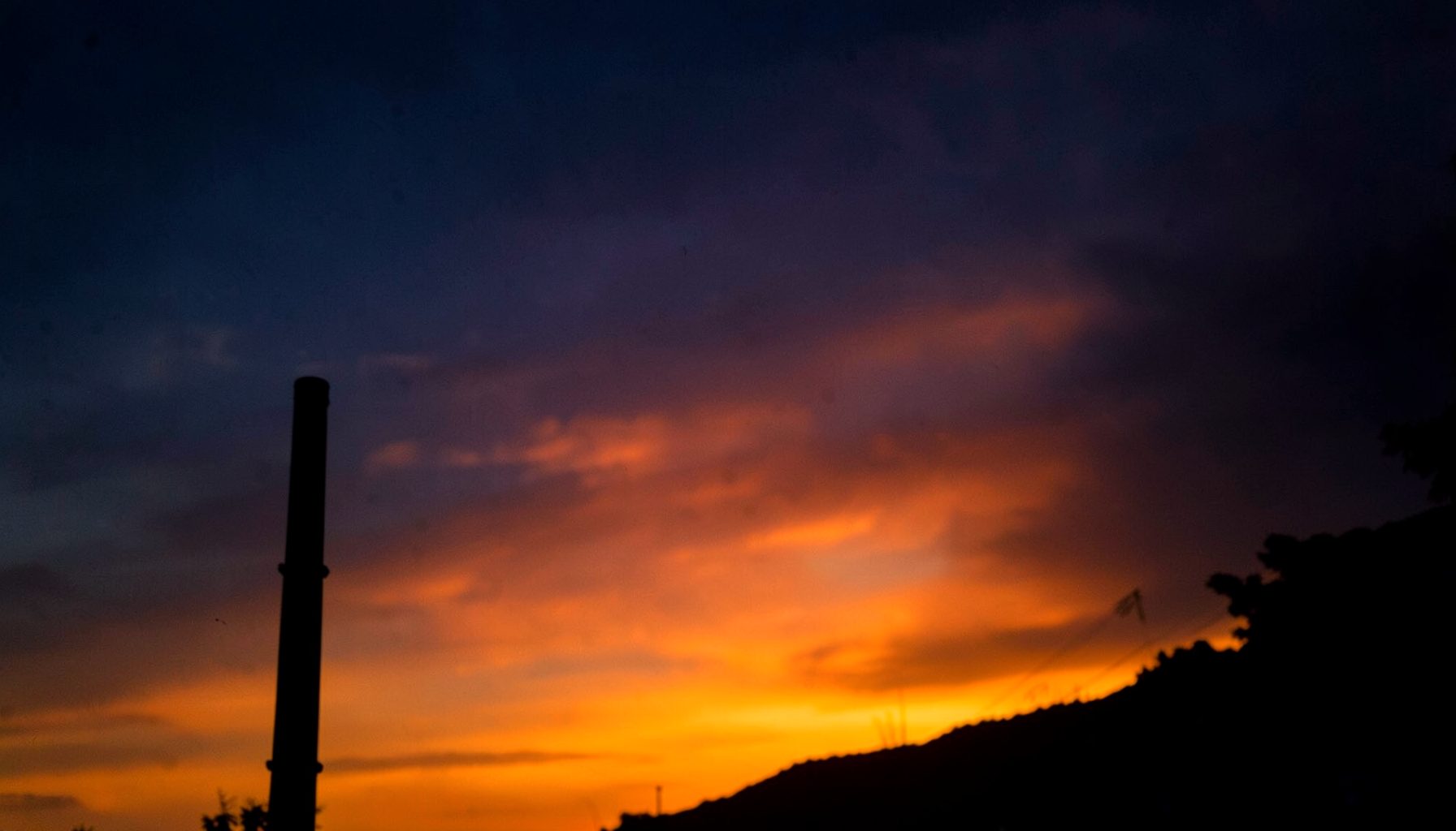 Corner flag silhouetted against a dramatic sunset sky, deep oranges fading into navy blue